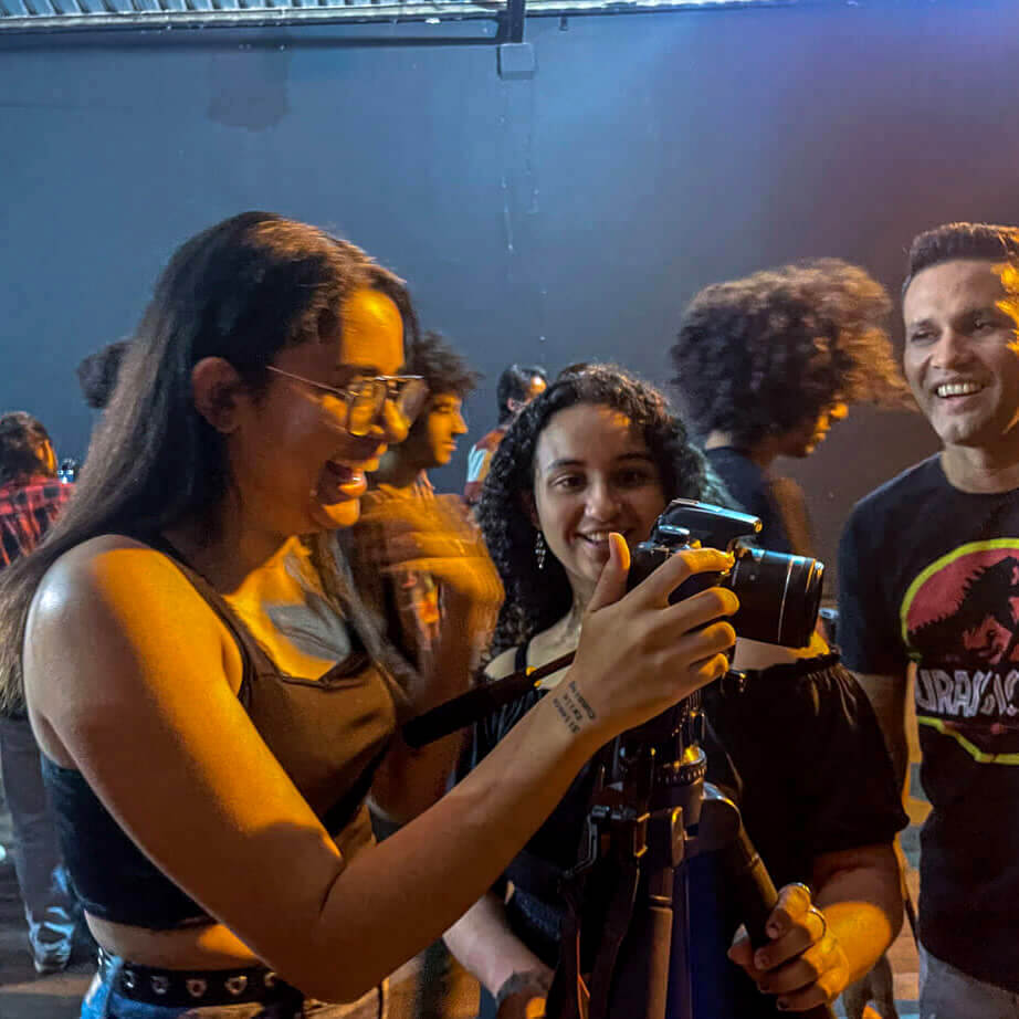 Mulheres sorrindo para a câmera em evento, uma segurando-a e a outra olhando.